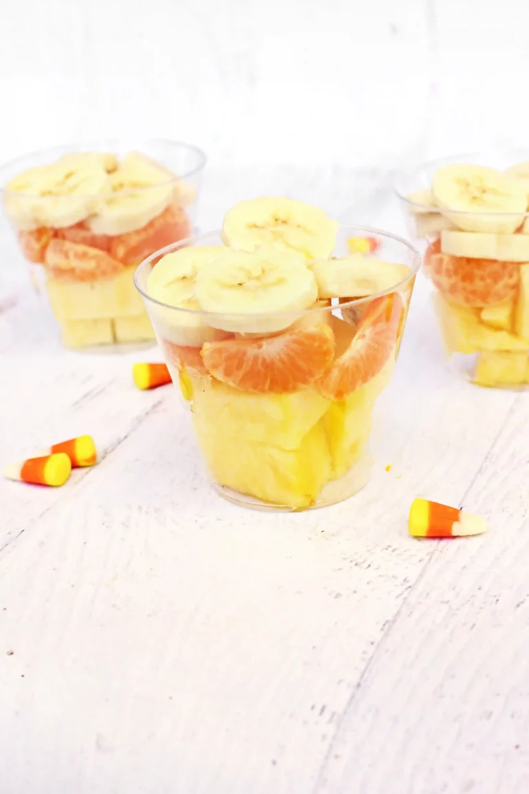 plastic cups with bananas, oranges, and pineapple in them