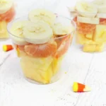 plastic cups with bananas, oranges, and pineapple in them