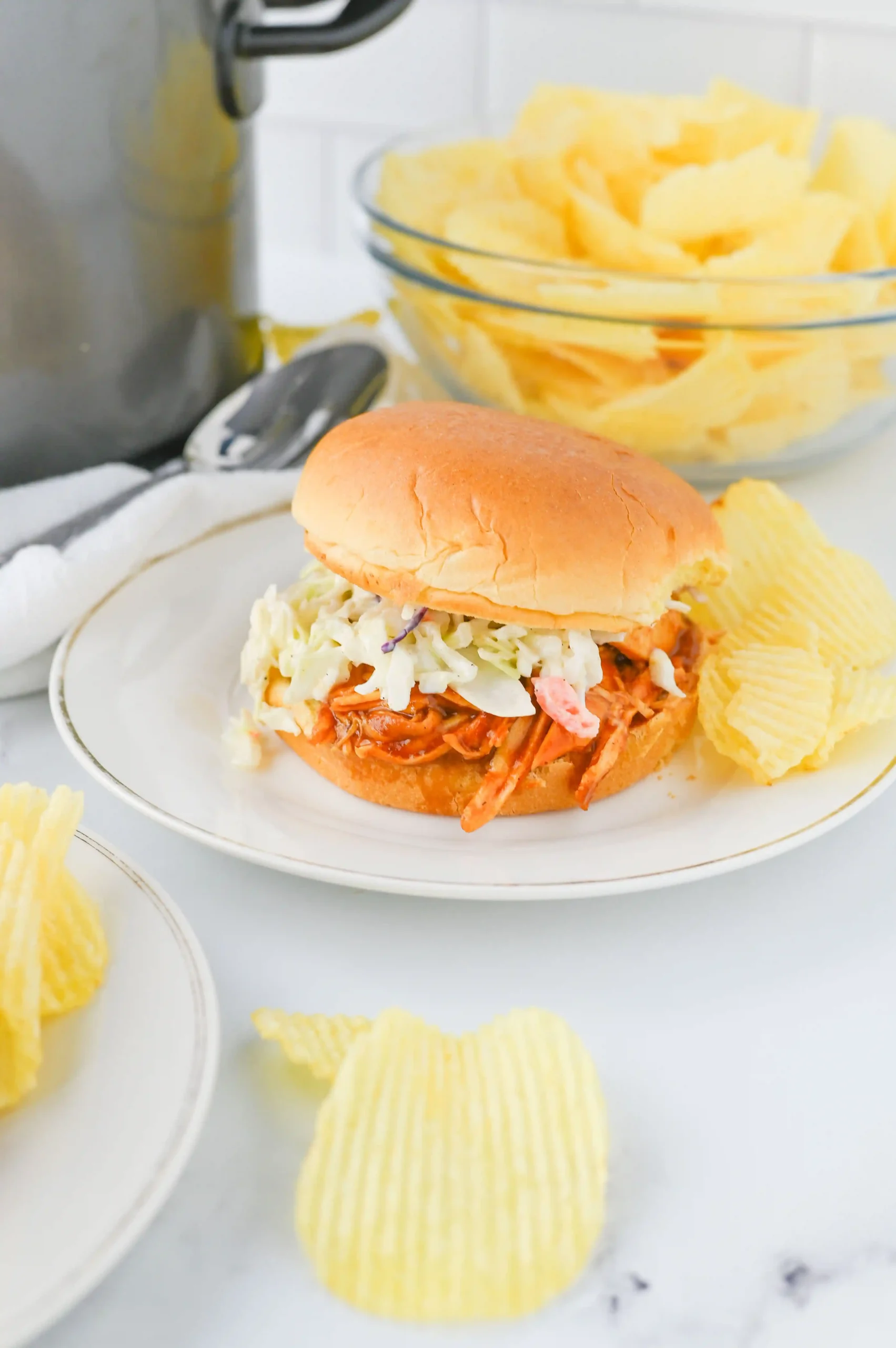 a barbecue chicken slider with coleslaw on a white plate