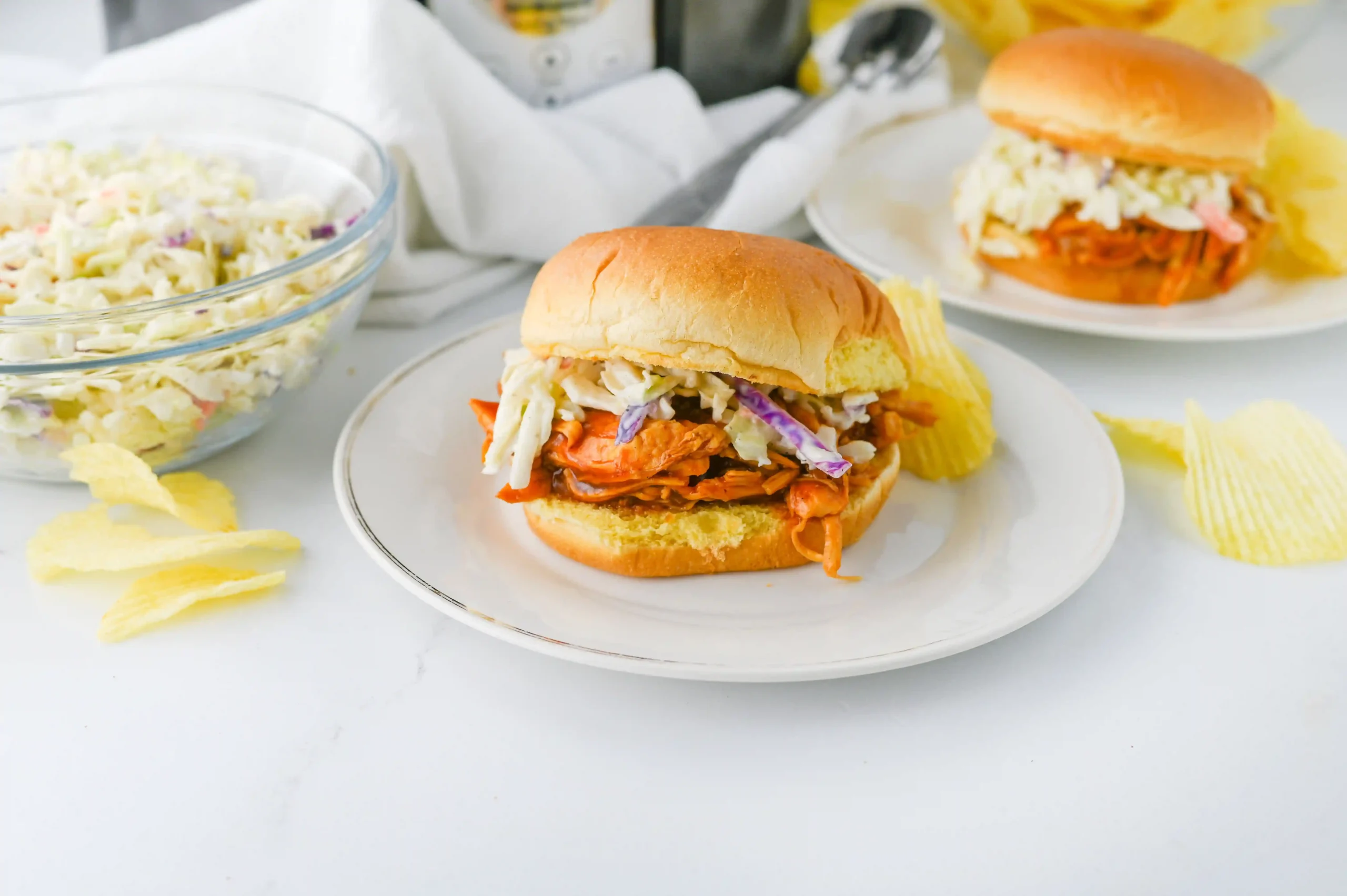 a barbecue chicken slider with coleslaw on a white plate
