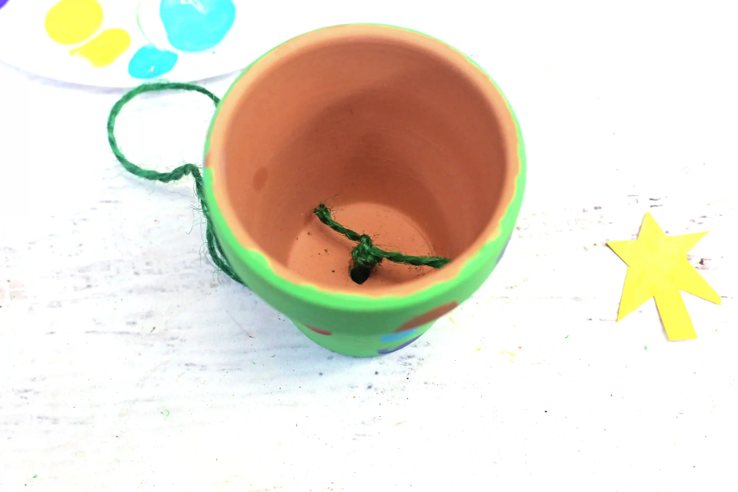 a clay pot painted green with green string tied inside to hang it