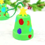 a clay pot painted green with fingerprint lights on it to make it look like a Christmas tree