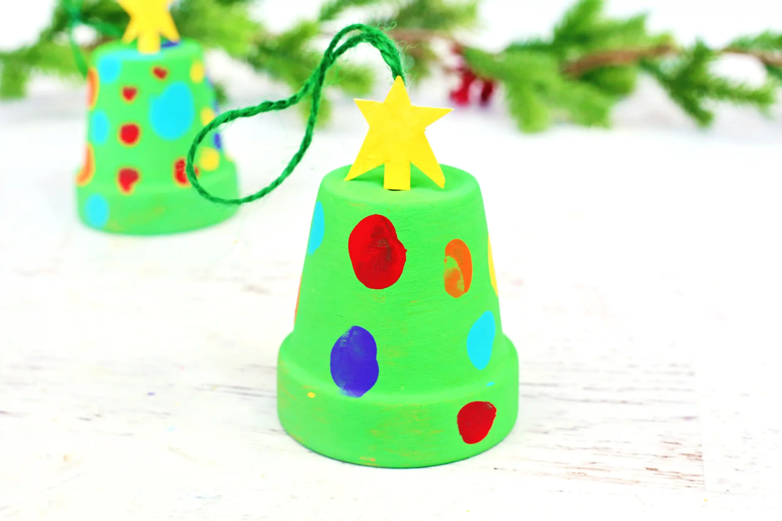 a clay pot painted green with fingerprint lights on it to make it look like a Christmas tree