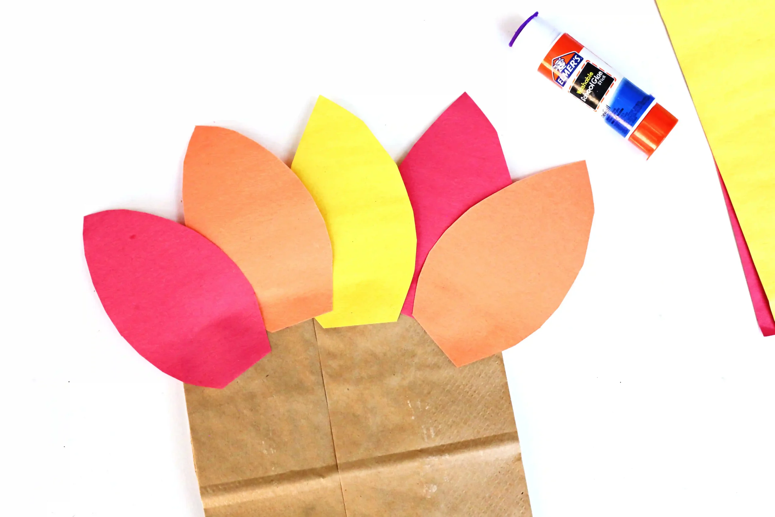 construction paper feathers glued to a paper bag