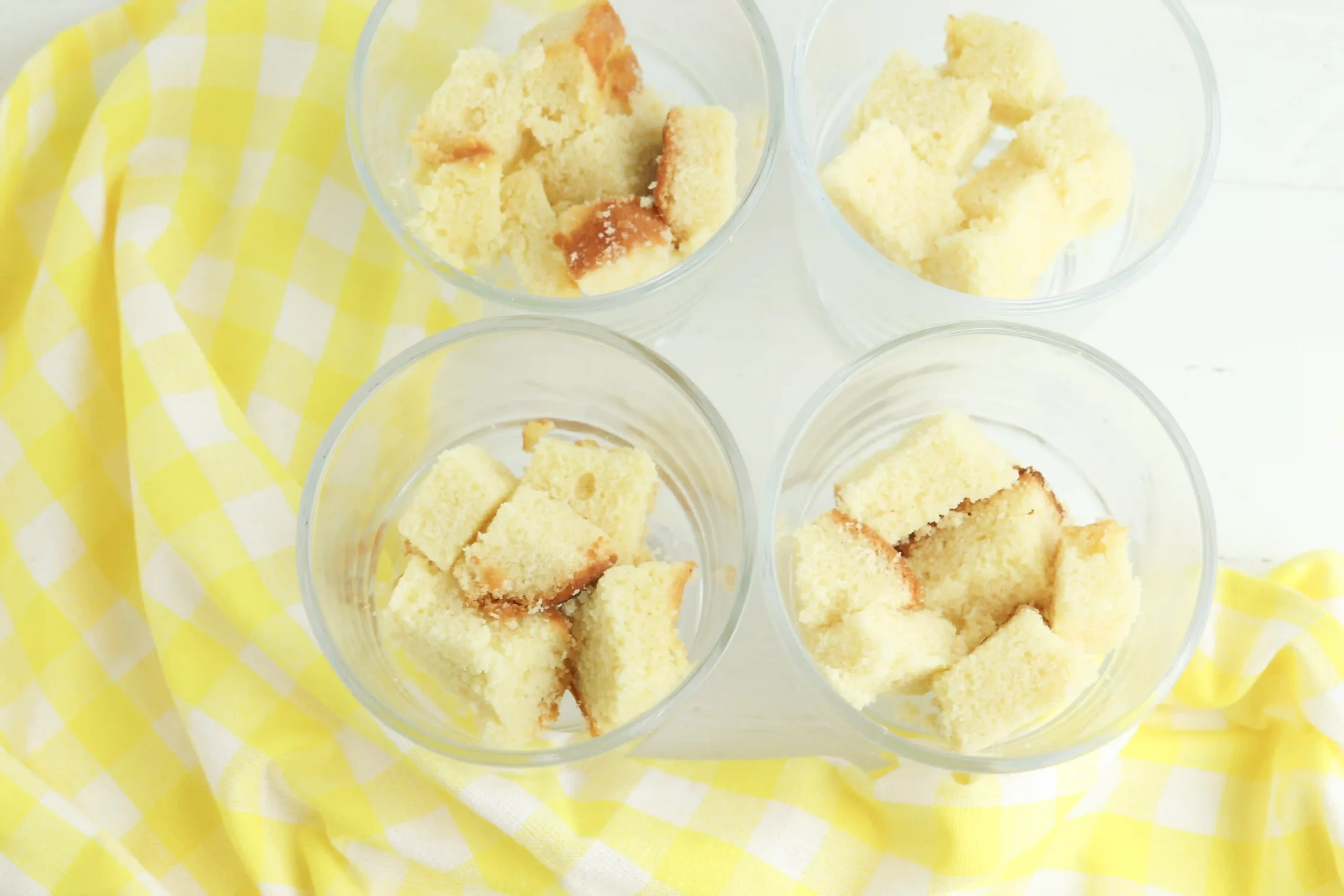 pound cake cut into chunks in trifle bowls next to a yellow towel