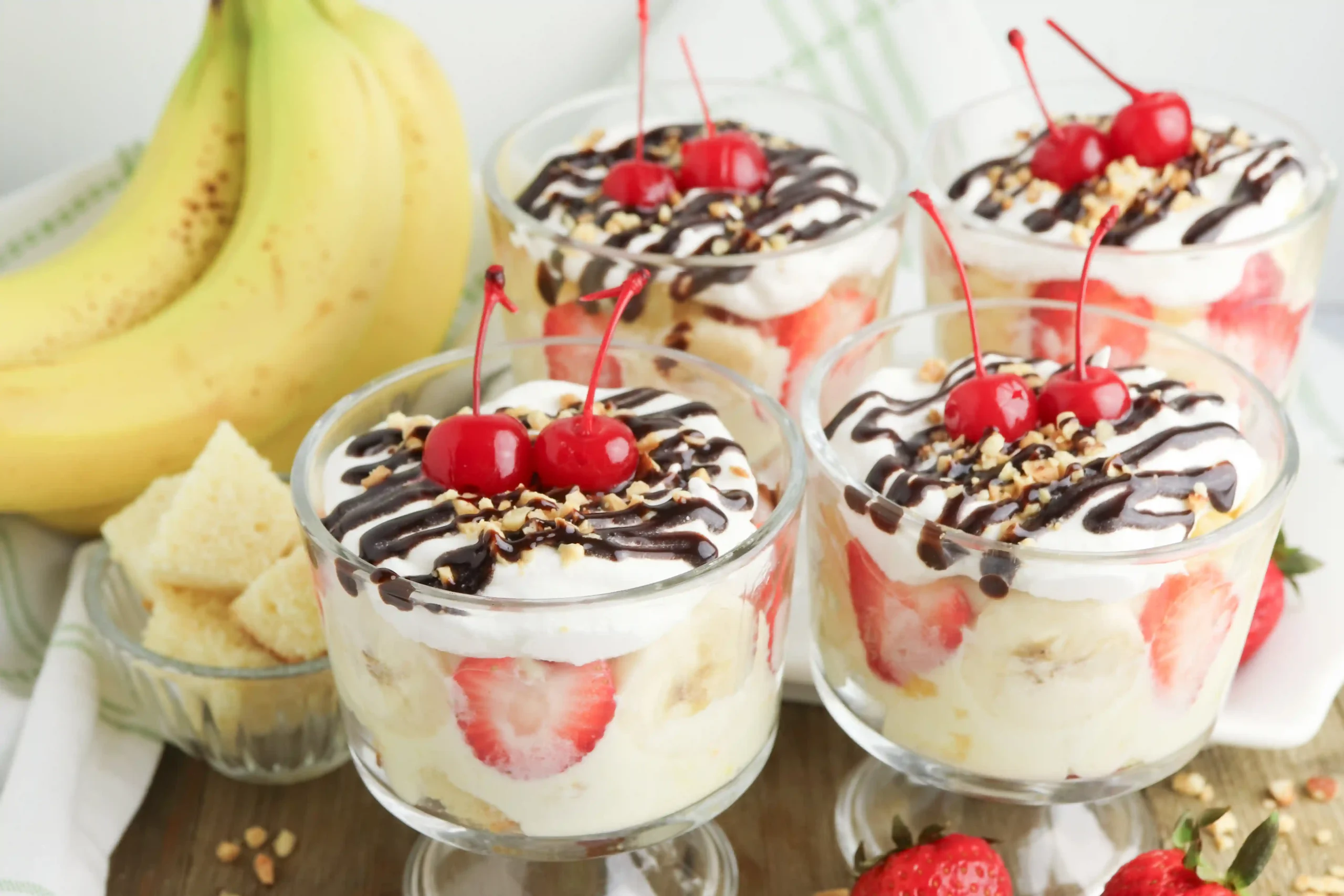 banana split trifle in a clear glass topped with cherries