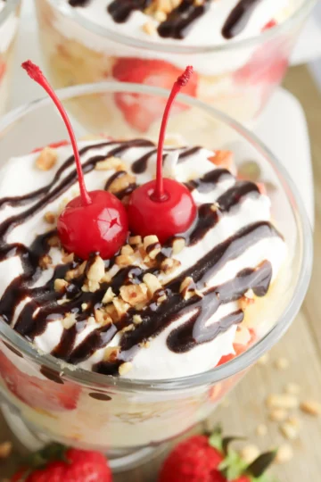 banana split trifle in a clear glass topped with cherries