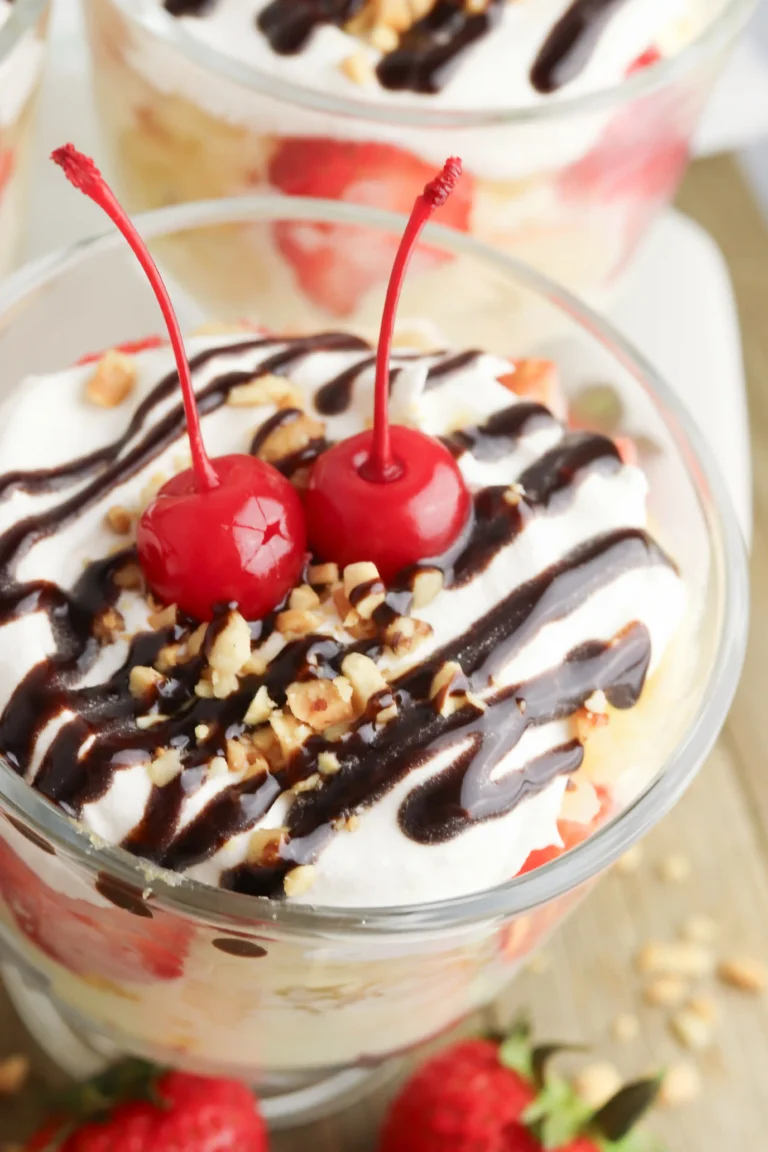 banana split trifle in a clear glass topped with cherries