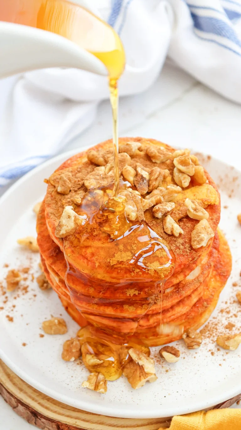 pumpkin pancakes with syrup and walnuts on a white plate